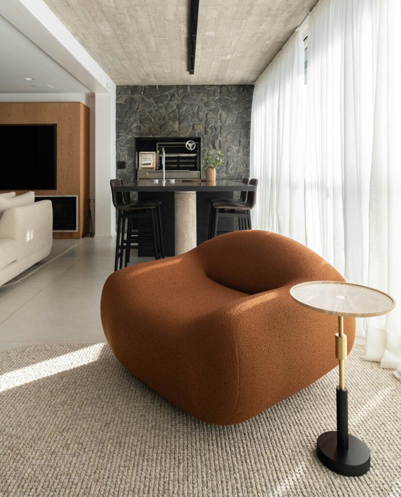 Ambiente residencial com poltrona moderna e área gourmet decorada para locação de móveis.